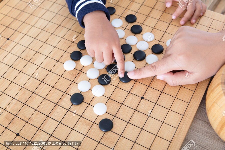 大人的手指导着小孩的手下围棋