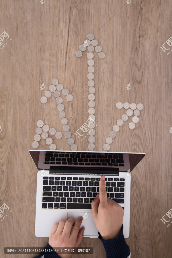 手操作电脑和硬币摆成的箭头符号