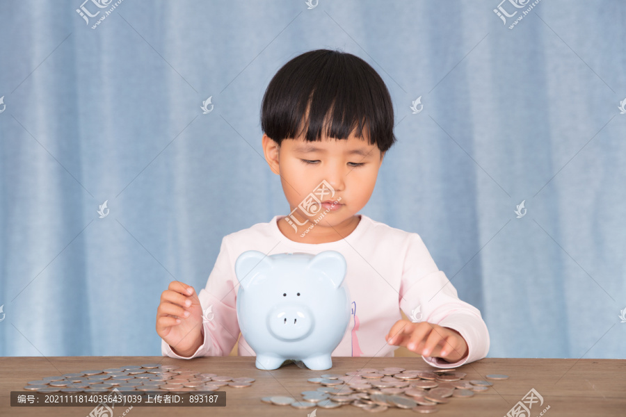 小姑娘在摆弄桌子上的小猪存钱罐