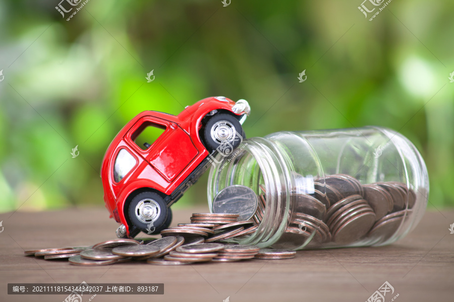 小汽车爬在一个倾倒的玻璃存钱罐