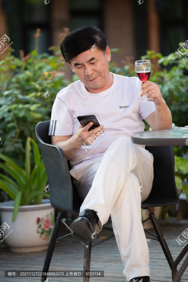 老年人在户外坐着喝红酒刷手机