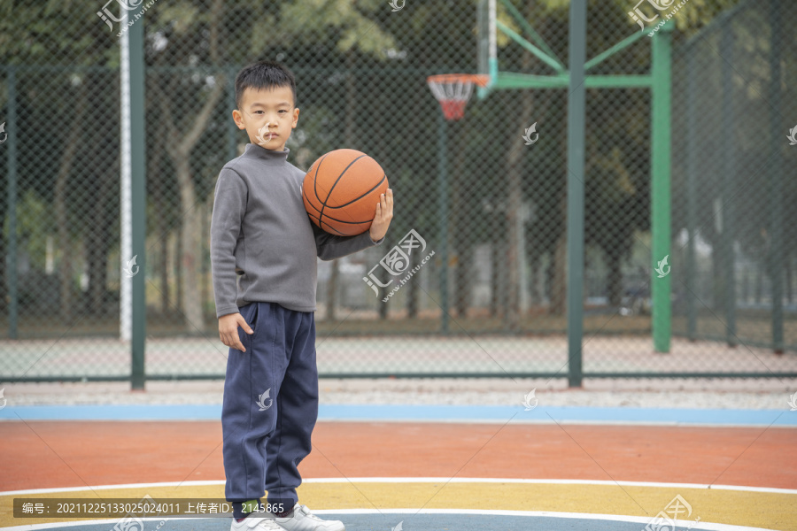 操场上抱着篮球的少年