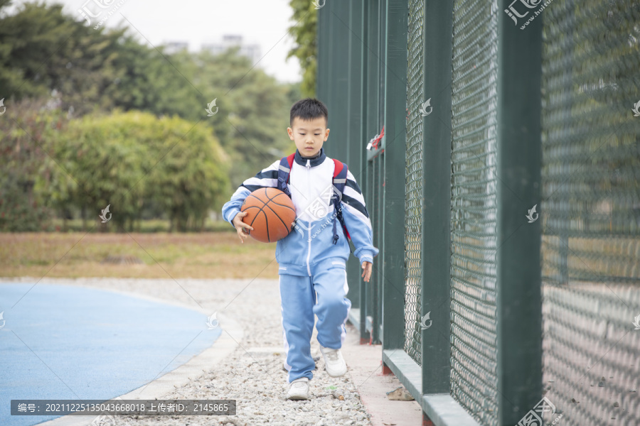 操场上抱着篮球的小学生