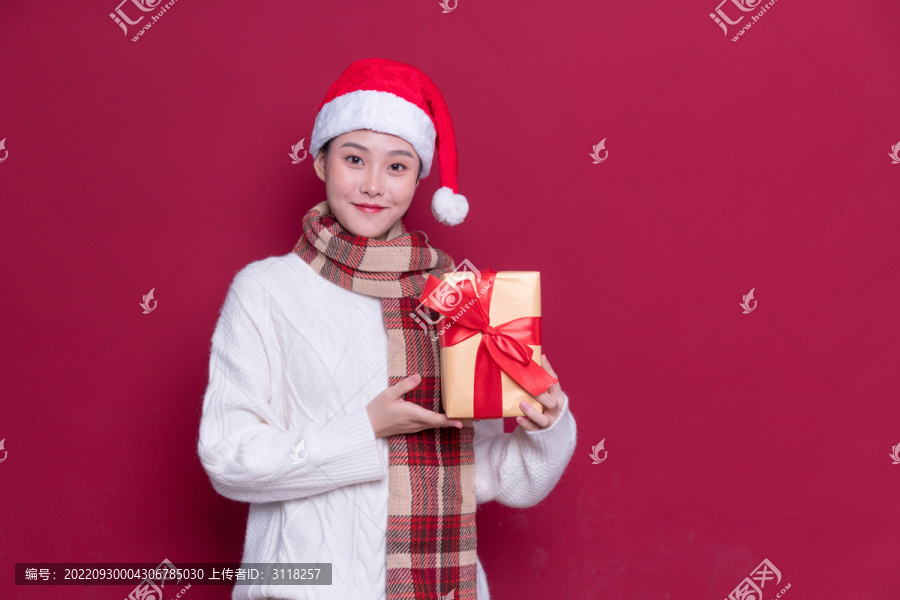 带着圣诞帽的女性拿着礼盒