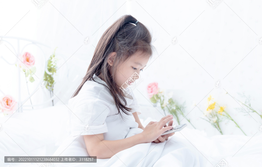 在床上玩手机的小女孩
