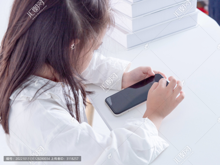 书桌上使用手机的小女孩俯视角