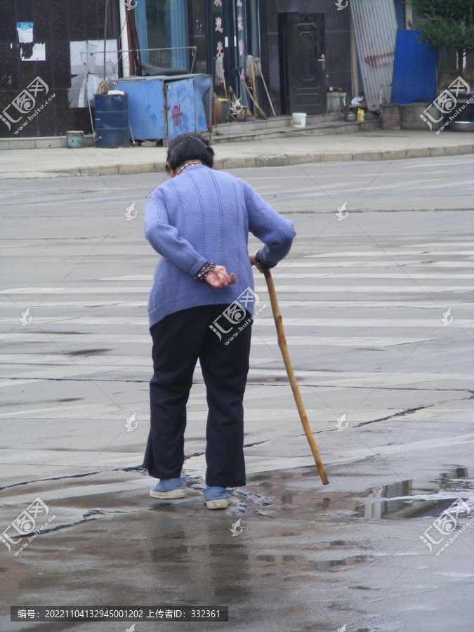 下雨天在路上行走的驼背老人