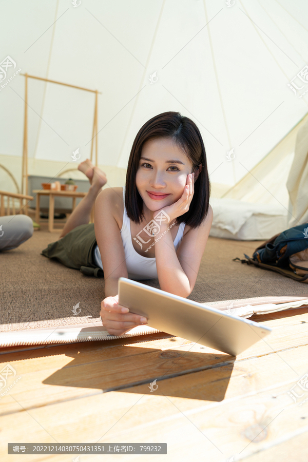 女孩坐帐篷里看平板电脑
