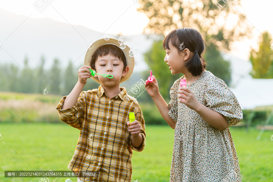 两个小孩在草地上吹泡泡