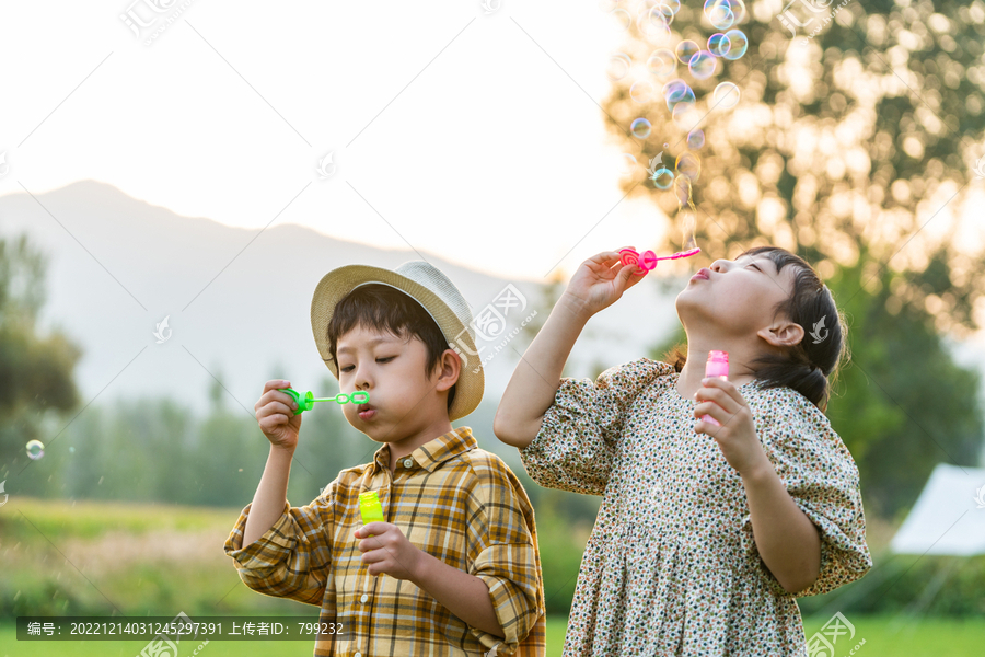 两个小孩在草地上吹泡泡