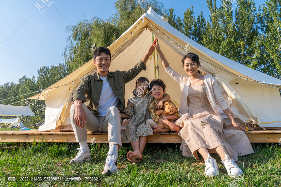 一家人坐在露营地的帐篷前