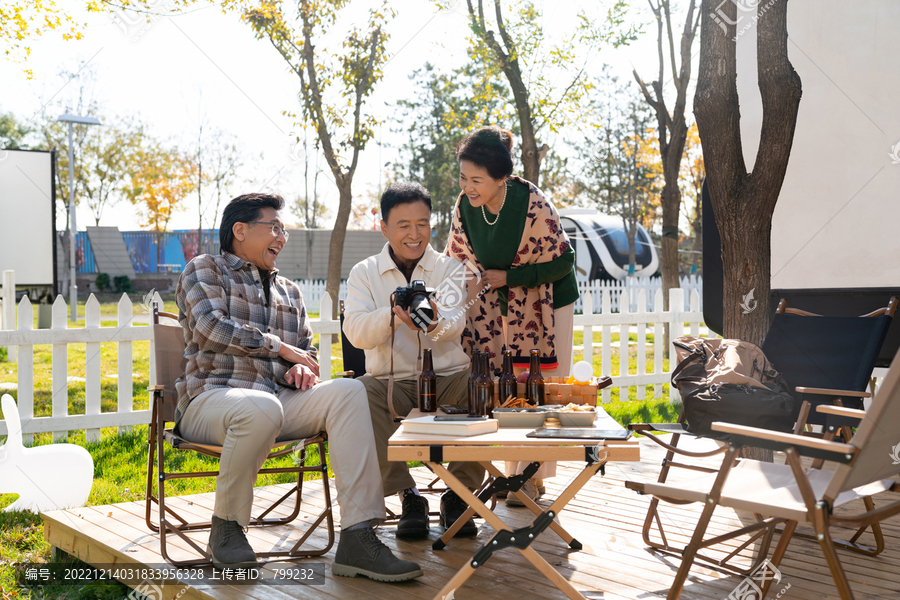 一群中老年人坐在露营地看数码相机