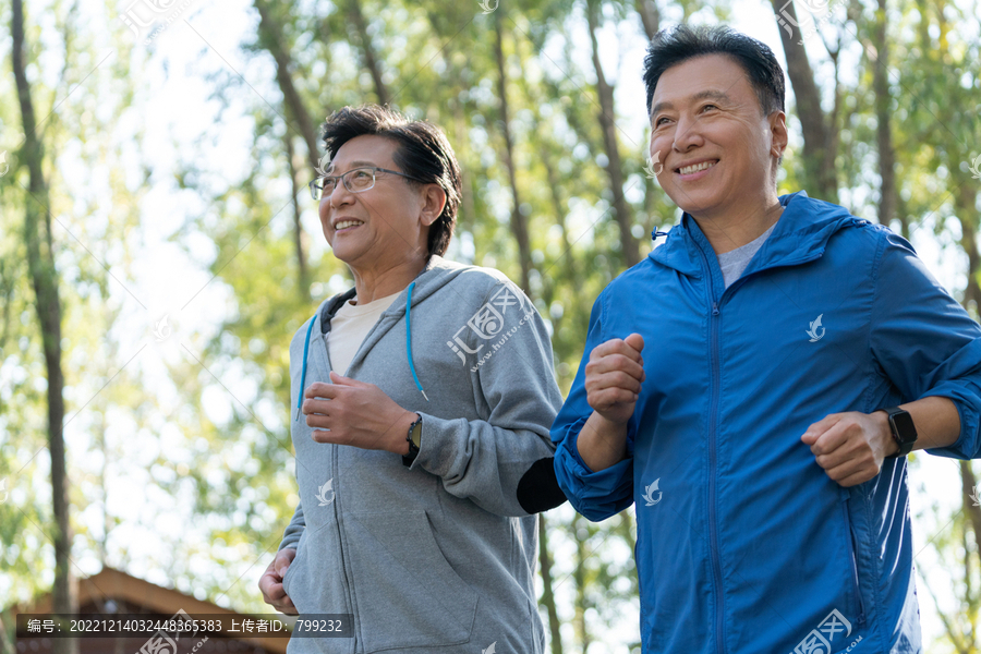 两个戴运动手表的中老年男人在树林跑步健身