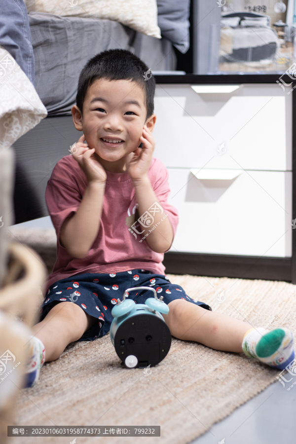 一个小男孩坐在地毯上玩闹钟
