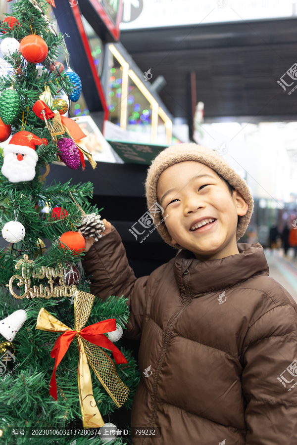 一个小男孩站在圣诞树旁边