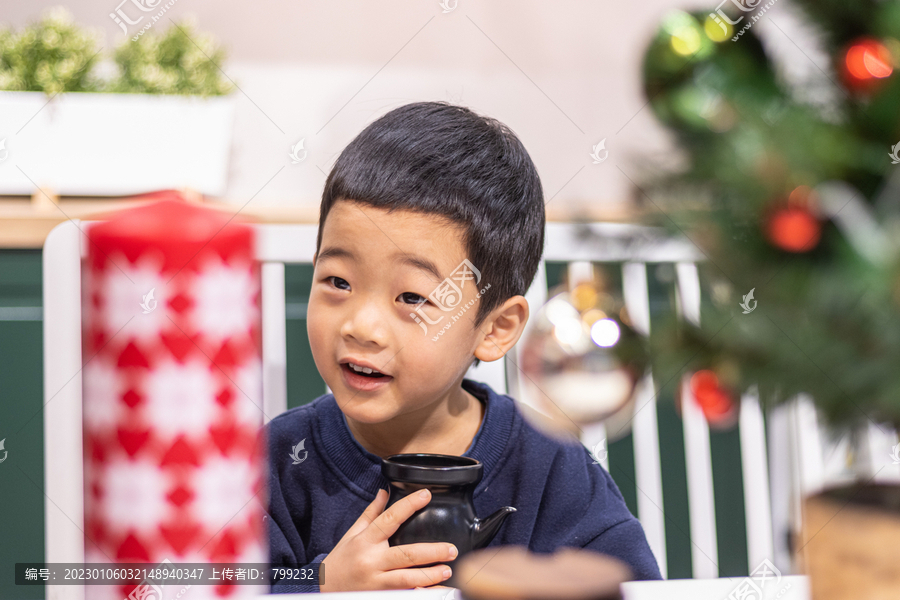 一个小男孩坐在圣诞节装饰桌旁