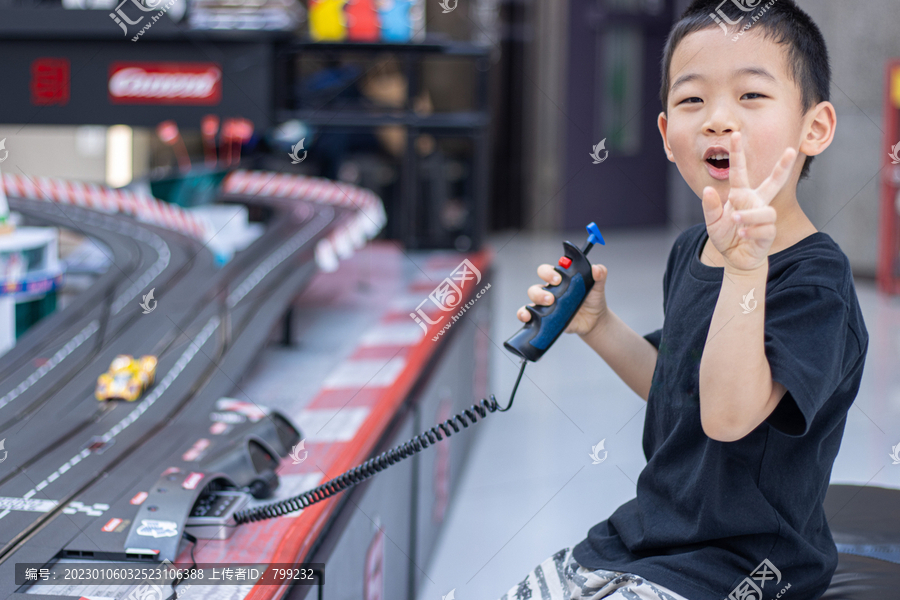 一个小男孩在游戏厅玩赛车玩具