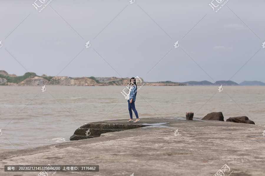 年轻女子站在码头看海