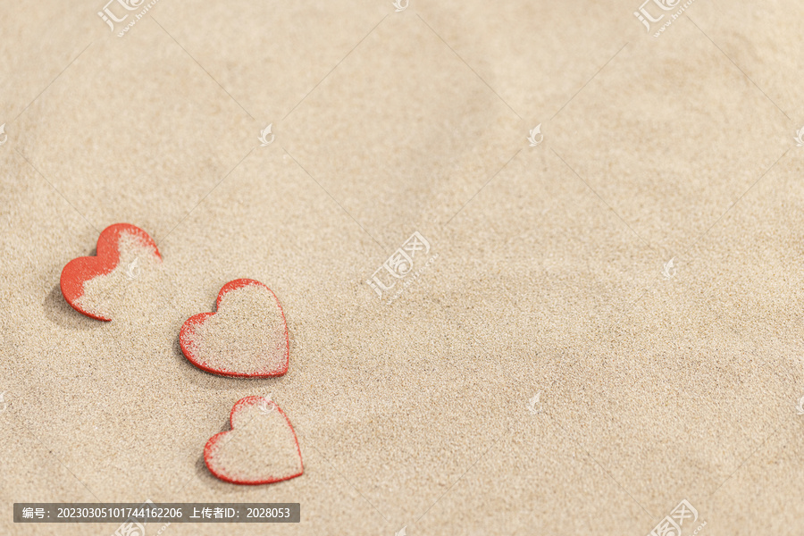 夏日沙滩上的三颗红色爱心