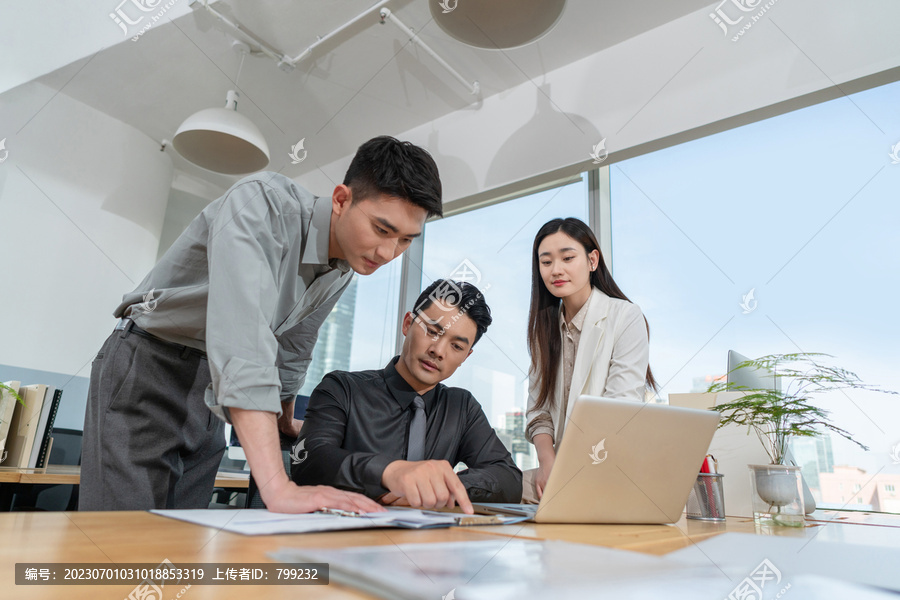 同事在办公桌前看电脑积极交流沟通工作