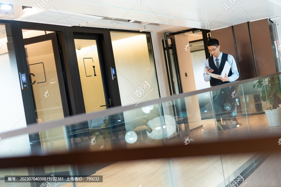 商务人士经过走廊看文件接电话
