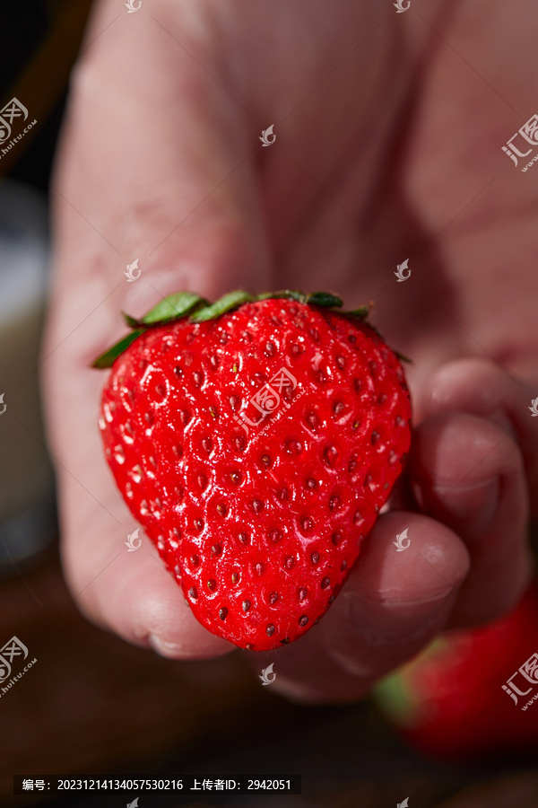 手拿着一个草莓