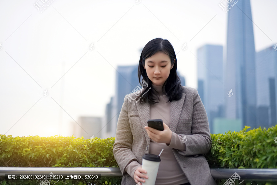 摩天大楼外职业女心茶歇看手机