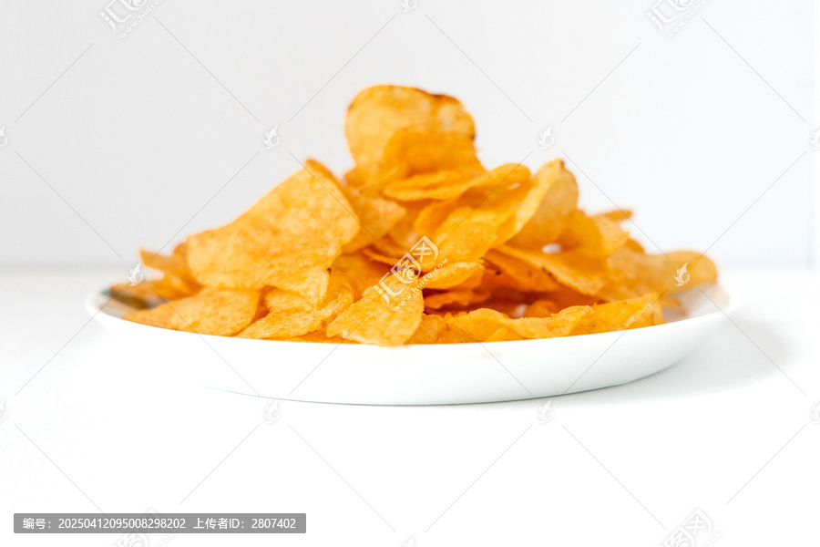 一盘白色彩绘碟子里装着一堆膨化薯片零食