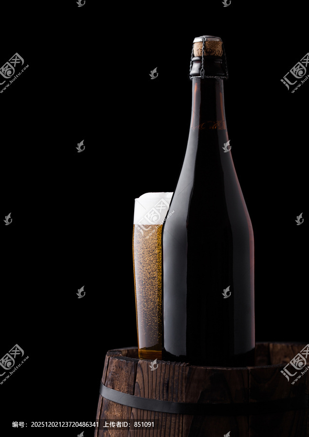 冷瓶和玻璃杯装的手工啤酒放在旧木桶上，黑色背景